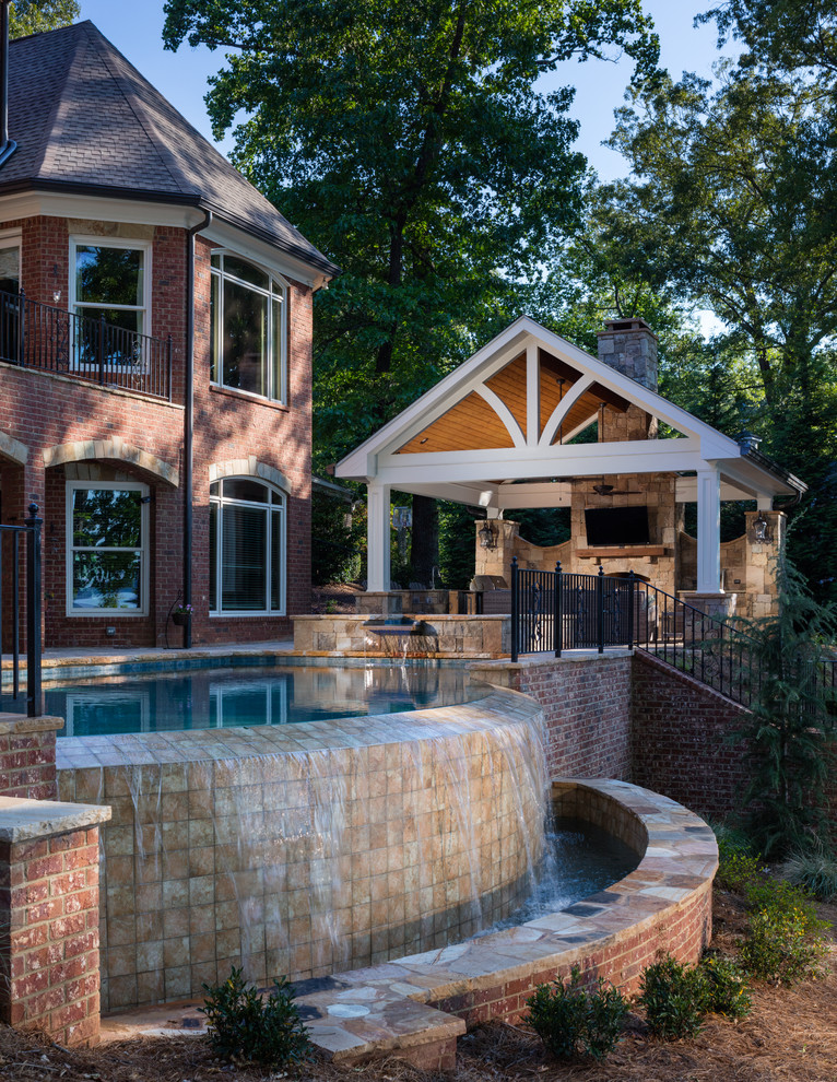 Imagen de piscina con fuente infinita clásica grande rectangular en patio trasero con adoquines de hormigón