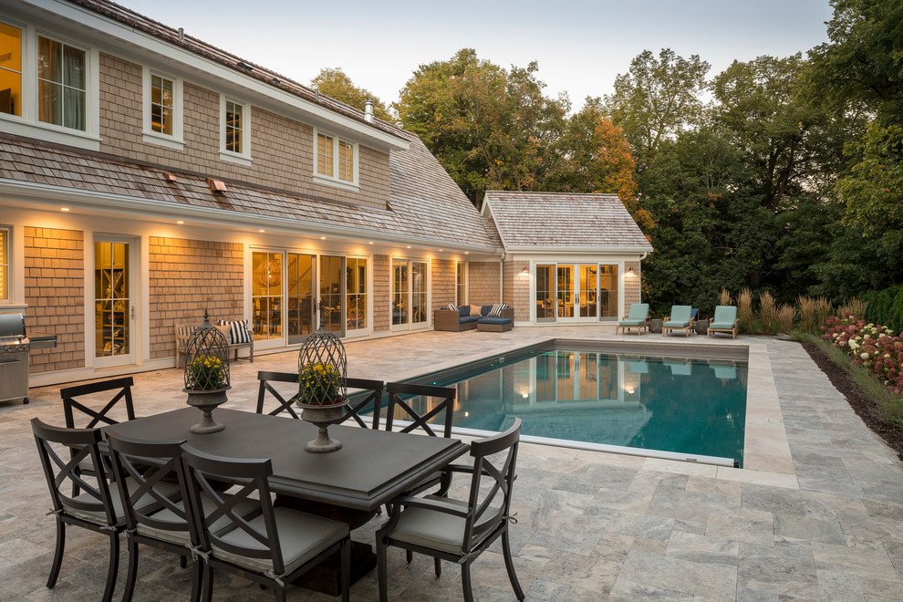 Modelo de casa de la piscina y piscina alargada costera de tamaño medio rectangular en patio trasero con adoquines de piedra natural