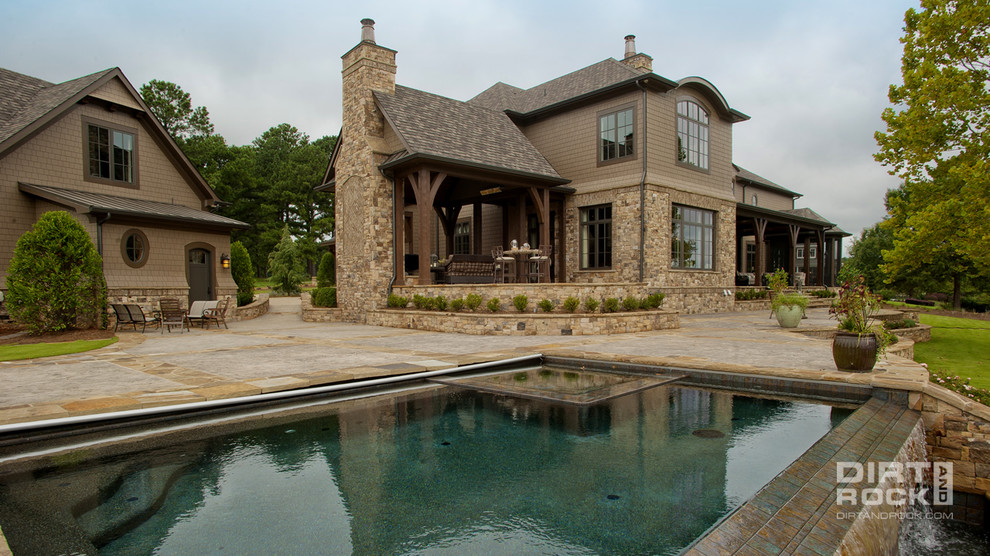 Diseño de piscina con fuente infinita clásica grande rectangular en patio con adoquines de piedra natural