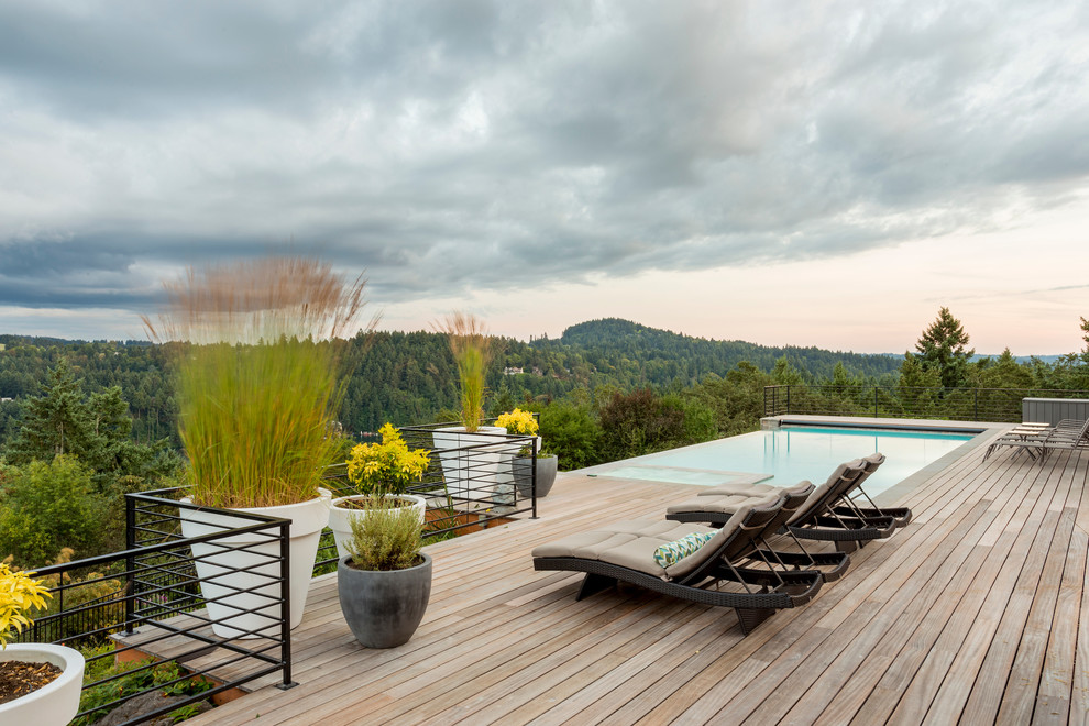 This is an example of a medium sized contemporary back rectangular infinity swimming pool in Portland with decking.