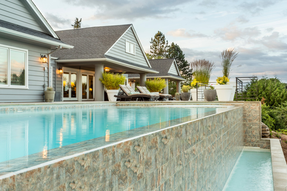 Esempio di una piscina a sfioro infinito tradizionale rettangolare di medie dimensioni e dietro casa con lastre di cemento e una vasca idromassaggio