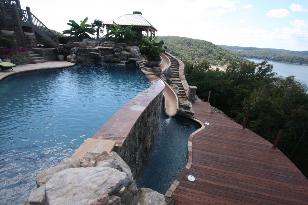 Idee per una grande piscina a sfioro infinito stile marinaro personalizzata dietro casa con un acquascivolo e pavimentazioni in pietra naturale