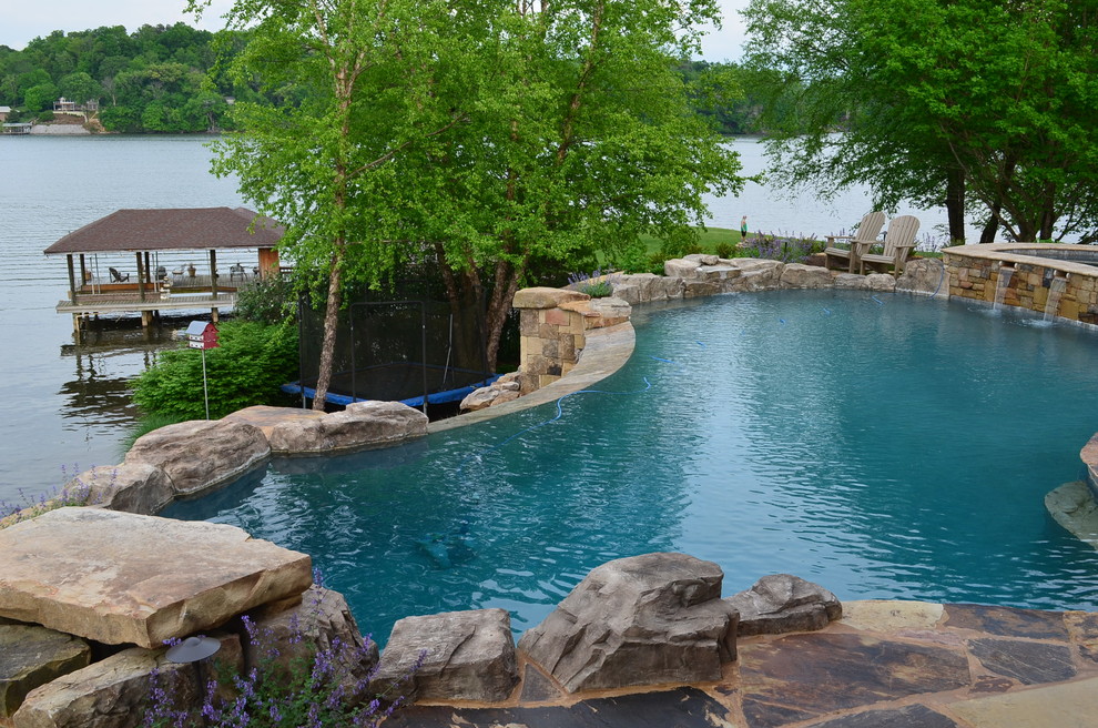 Foto di un'ampia piscina a sfioro infinito tradizionale personalizzata dietro casa con fontane e pavimentazioni in pietra naturale