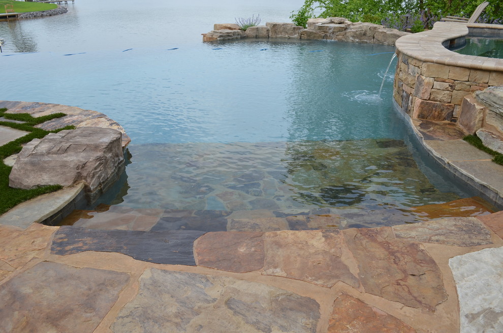 Idee per un'ampia piscina a sfioro infinito chic personalizzata dietro casa con fontane e pavimentazioni in pietra naturale