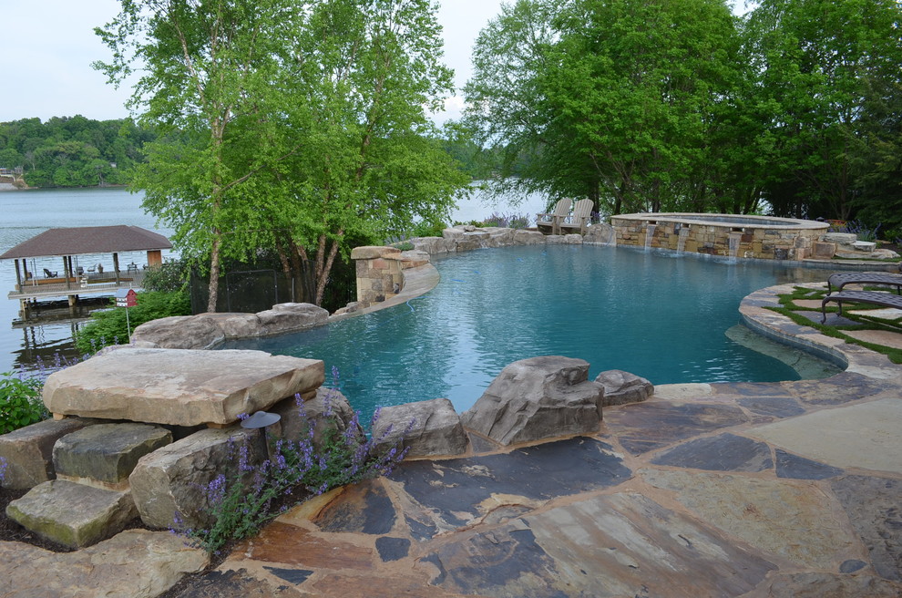 Geräumiger Klassischer Infinity-Pool hinter dem Haus in individueller Form mit Wasserspiel und Natursteinplatten in Sonstige