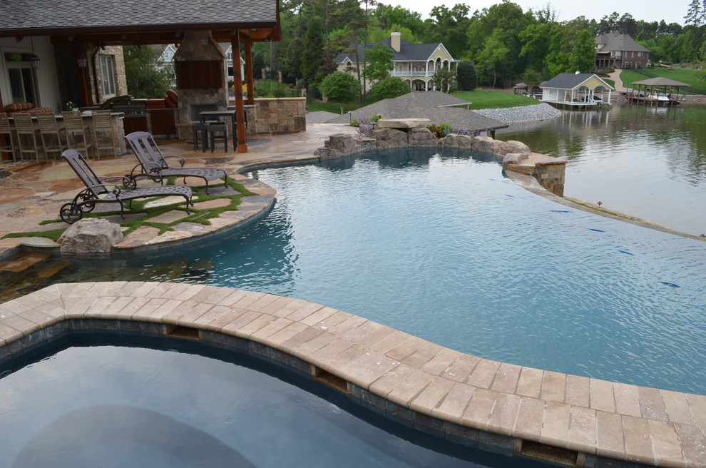 Cette image montre une très grande piscine à débordement et arrière traditionnelle sur mesure avec un point d'eau et des pavés en pierre naturelle.