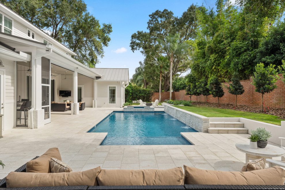 Modelo de piscina con fuente alargada costera grande rectangular en patio trasero con adoquines de piedra natural