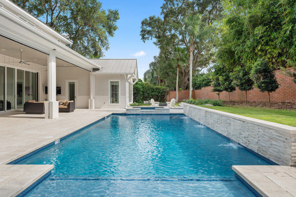 Diseño de piscina con fuente alargada marinera grande rectangular en patio trasero con adoquines de piedra natural