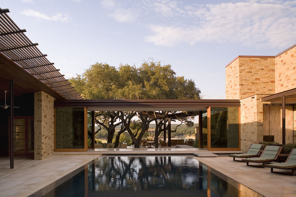 Ejemplo de piscina infinita contemporánea grande rectangular en patio con suelo de baldosas