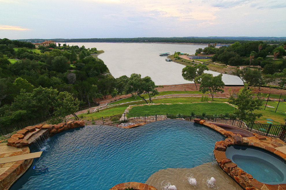 Großer Maritimer Infinity-Pool hinter dem Haus in individueller Form mit Wasserrutsche und Natursteinplatten in Austin