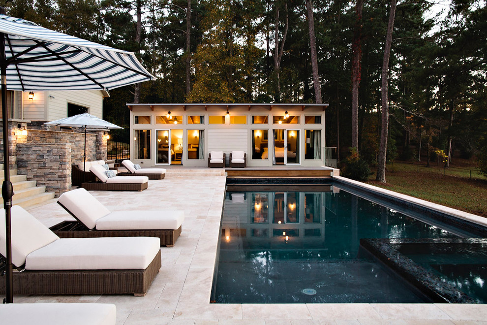 На фото: большой прямоугольный бассейн на заднем дворе с покрытием из каменной брусчатки с