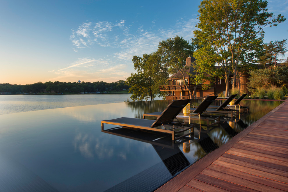 Cette image montre une piscine à débordement design avec une terrasse en bois.