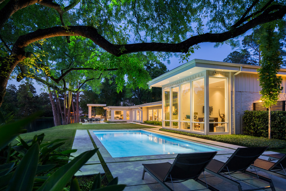 Imagen de piscina contemporánea de tamaño medio rectangular en patio trasero con losas de hormigón