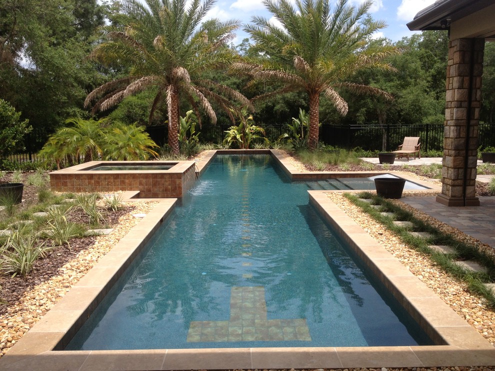 Foto de piscina alargada tropical grande rectangular en patio trasero con gravilla