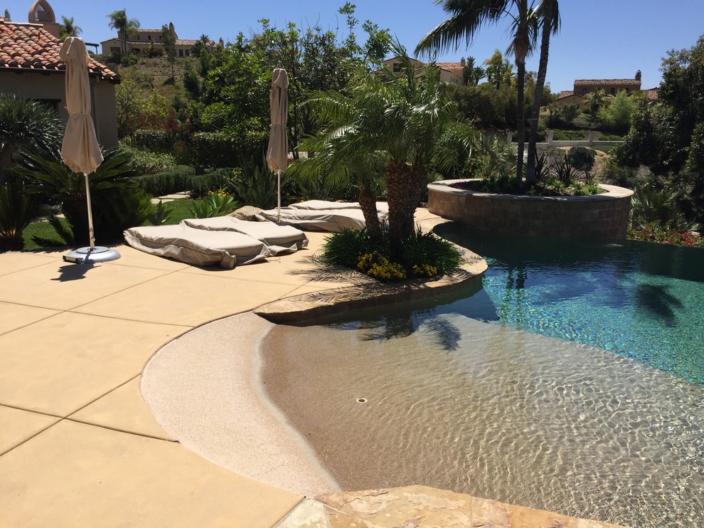 Esempio di una piscina a sfioro infinito stile marinaro personalizzata di medie dimensioni e dietro casa con lastre di cemento