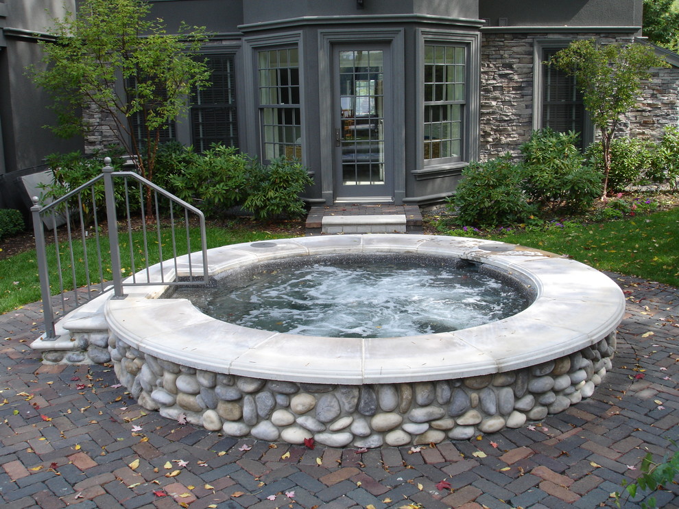 Cette photo montre une très grande piscine intérieure chic sur mesure avec un bain bouillonnant et des pavés en pierre naturelle.