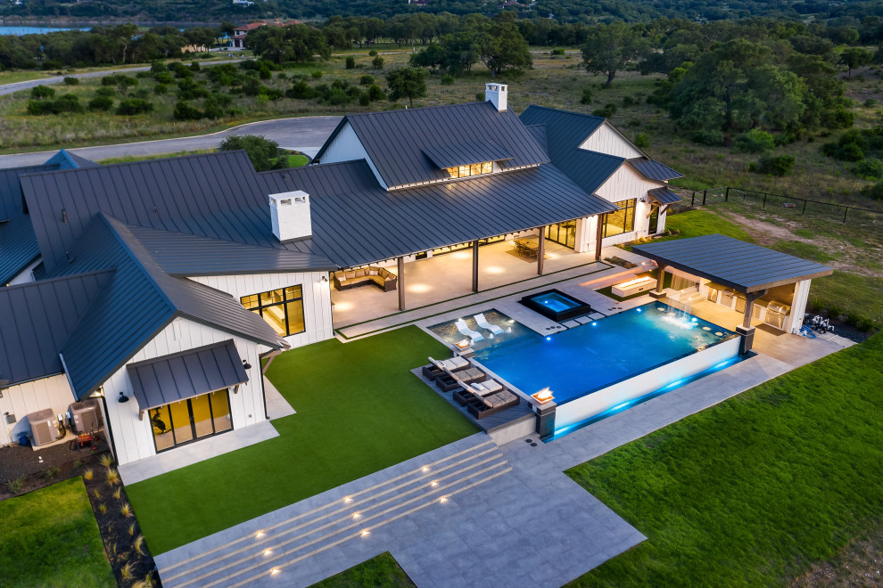 Exemple d'une grande piscine à débordement et arrière moderne rectangle avec une terrasse en bois.