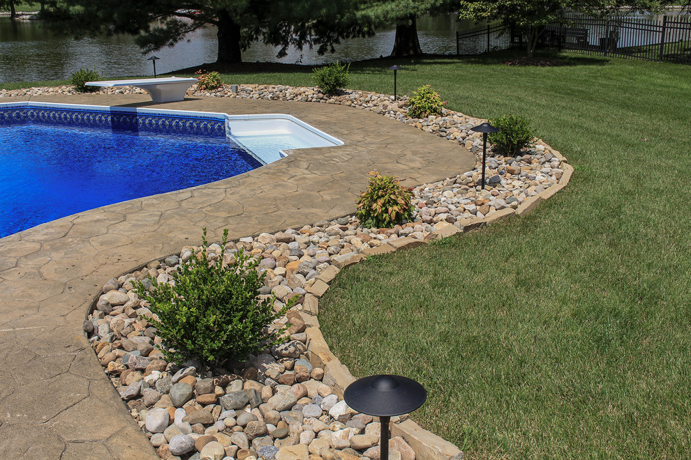 Exemple d'une grande piscine arrière chic en forme de haricot avec des pavés en pierre naturelle.
