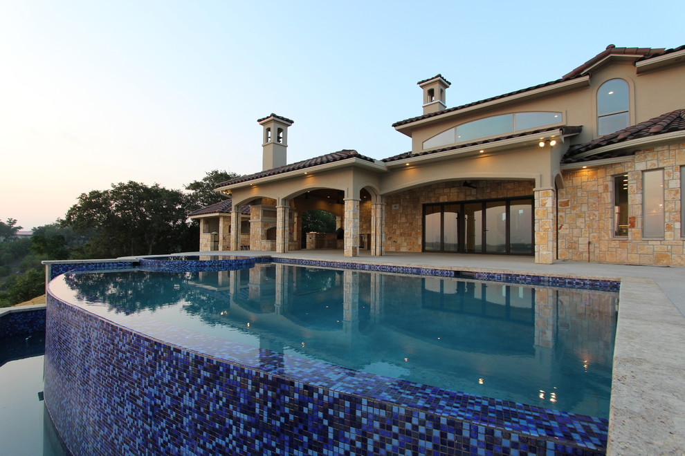 Immagine di una grande piscina monocorsia mediterranea rettangolare dietro casa con una vasca idromassaggio e piastrelle
