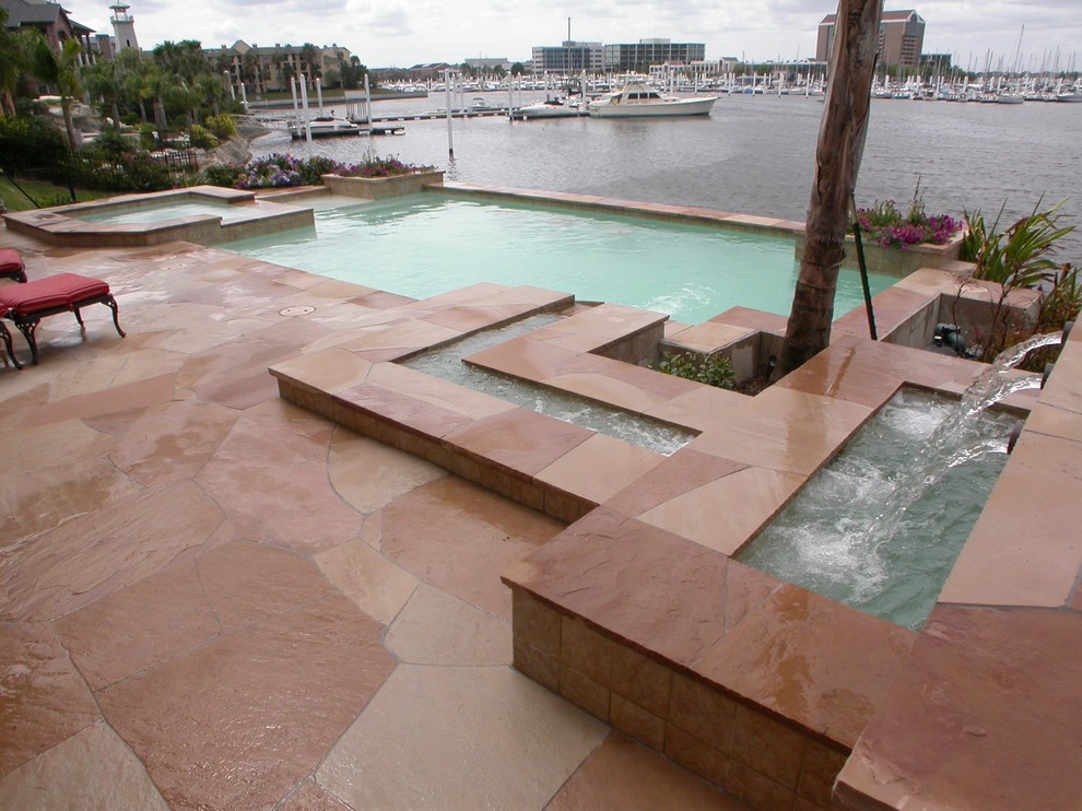 Cette image montre une grande piscine arrière design sur mesure avec un point d'eau et du béton estampé.