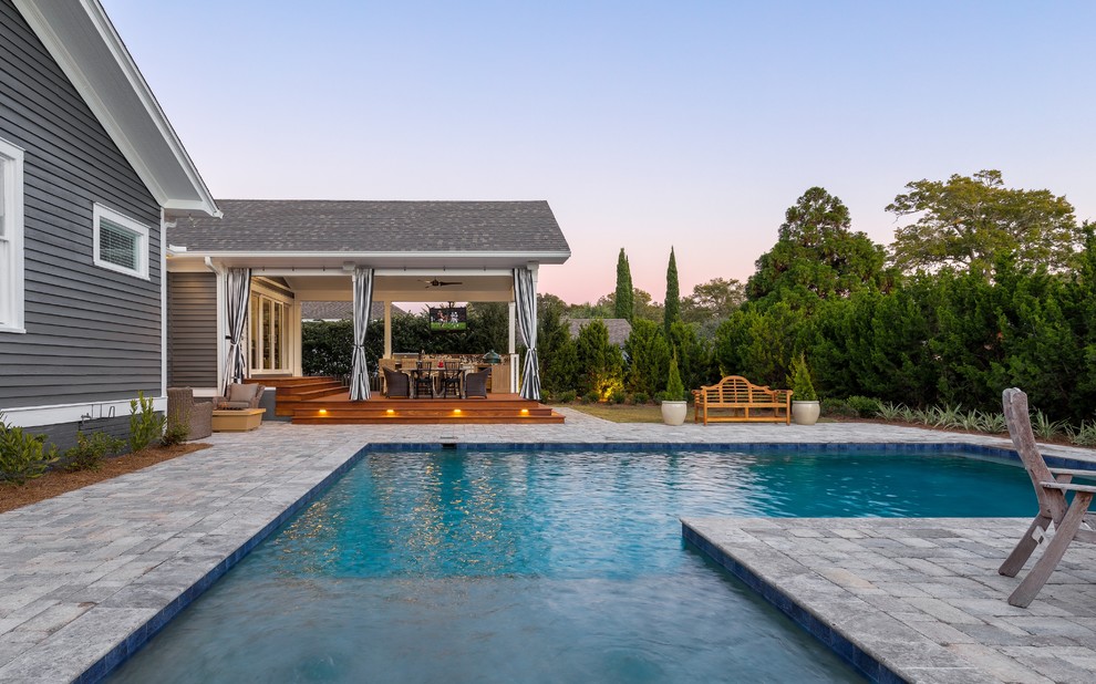 Diseño de casa de la piscina y piscina alargada clásica renovada grande en forma de L en patio trasero con adoquines de hormigón