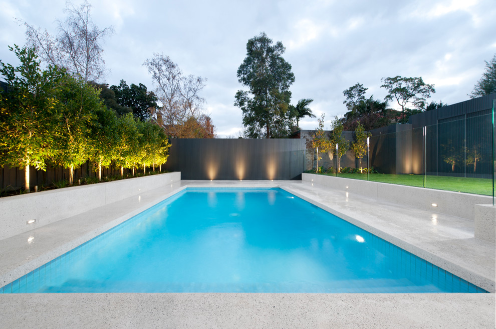 Пример оригинального дизайна: большой прямоугольный бассейн на заднем дворе в стиле модернизм с забором