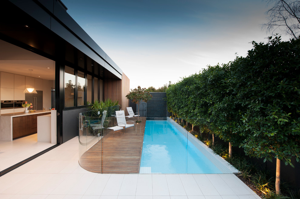 На фото: маленький спортивный, прямоугольный бассейн на заднем дворе в стиле модернизм с настилом и забором для на участке и в саду с