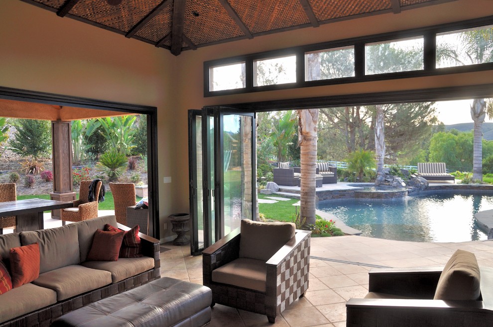 Modelo de casa de la piscina y piscina tropical grande a medida en patio trasero con losas de hormigón