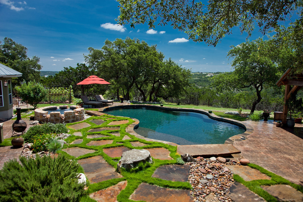 Traditional custom shaped swimming pool in Austin with natural stone paving.