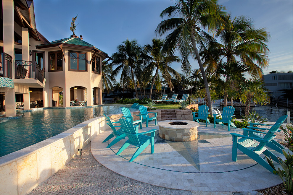 Modelo de piscina con fuente tropical grande a medida en patio trasero con gravilla