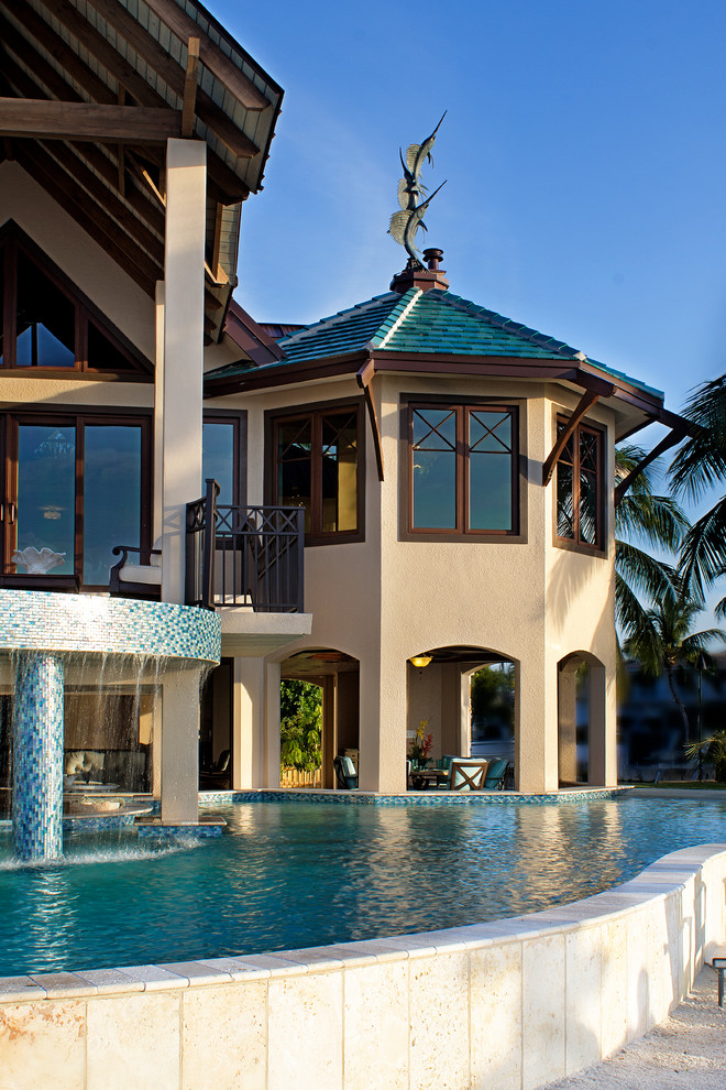 Bild på en stor tropisk anpassad pool på baksidan av huset, med en fontän och grus