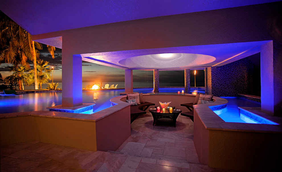 Immagine di una grande piscina tropicale personalizzata dietro casa con fontane