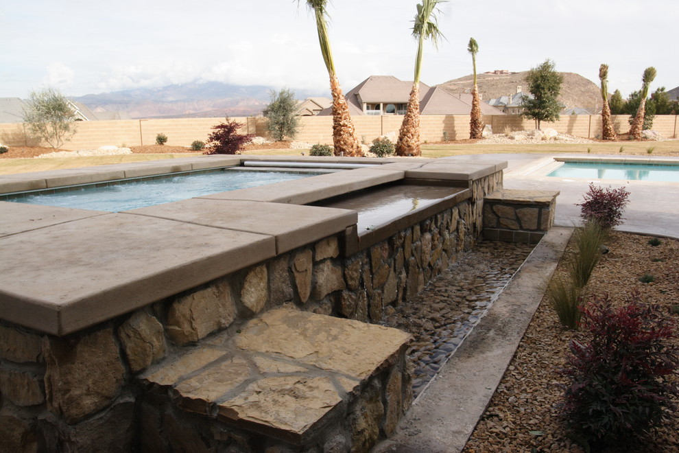 Immagine di una piscina monocorsia chic rettangolare di medie dimensioni e dietro casa con una vasca idromassaggio e lastre di cemento