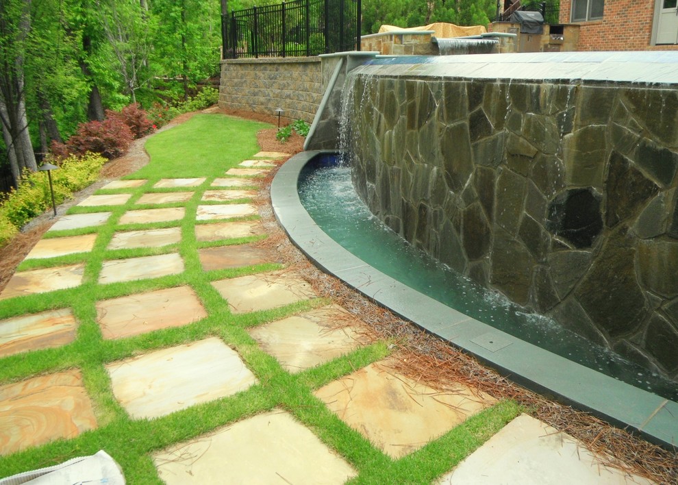 Diseño de piscina con fuente infinita de tamaño medio redondeada en patio trasero
