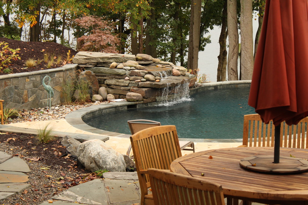 Cette image montre une piscine naturelle et arrière traditionnelle en forme de haricot de taille moyenne avec des pavés en pierre naturelle et un point d'eau.