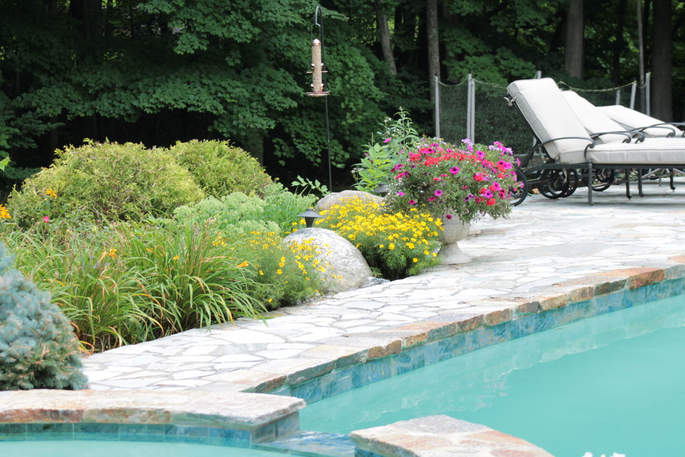 Ispirazione per una grande piscina minimalista personalizzata dietro casa con una vasca idromassaggio e pavimentazioni in pietra naturale