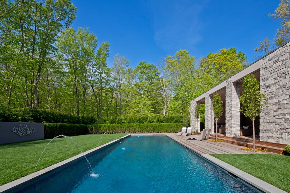 Inspiration for a modern backyard rectangular pool fountain remodel in New York with decking