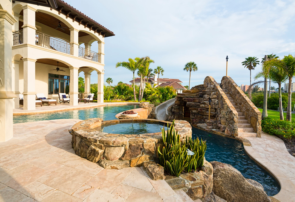 Diseño de piscina con tobogán natural mediterránea grande en patio trasero