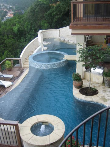 Photo of a large contemporary back custom shaped hot tub in Austin with natural stone paving.