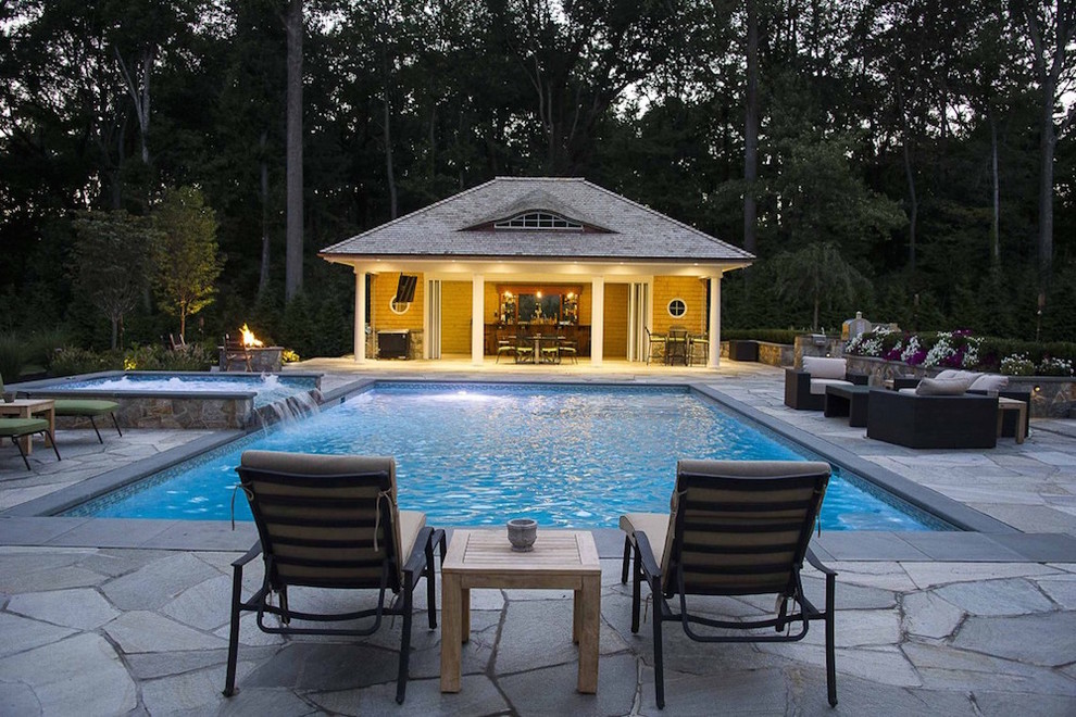 Immagine di una piscina moderna rettangolare dietro casa con una dépendance a bordo piscina e pavimentazioni in pietra naturale