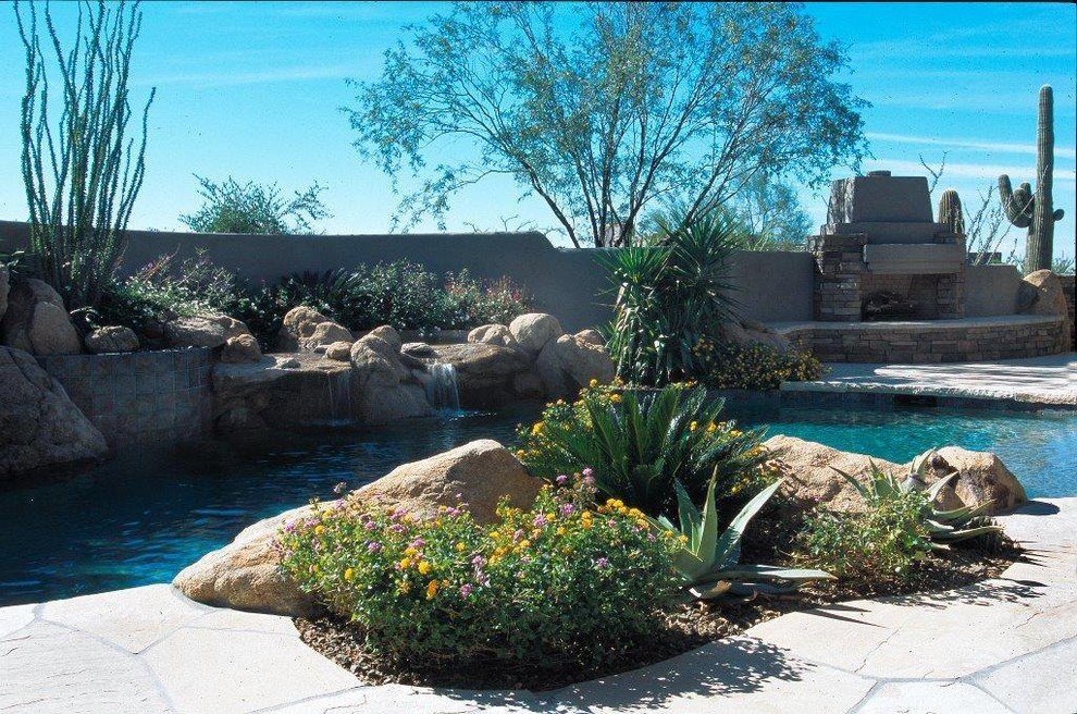 Photo of a medium sized modern back custom shaped infinity hot tub in Phoenix with natural stone paving.