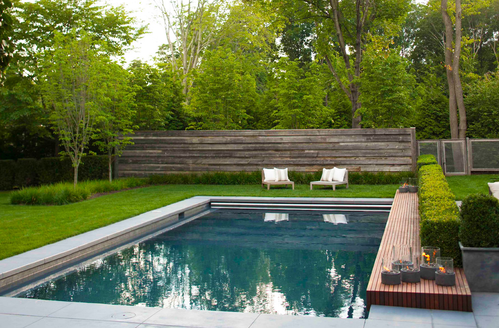 Foto de piscina alargada minimalista de tamaño medio rectangular en patio trasero con adoquines de piedra natural