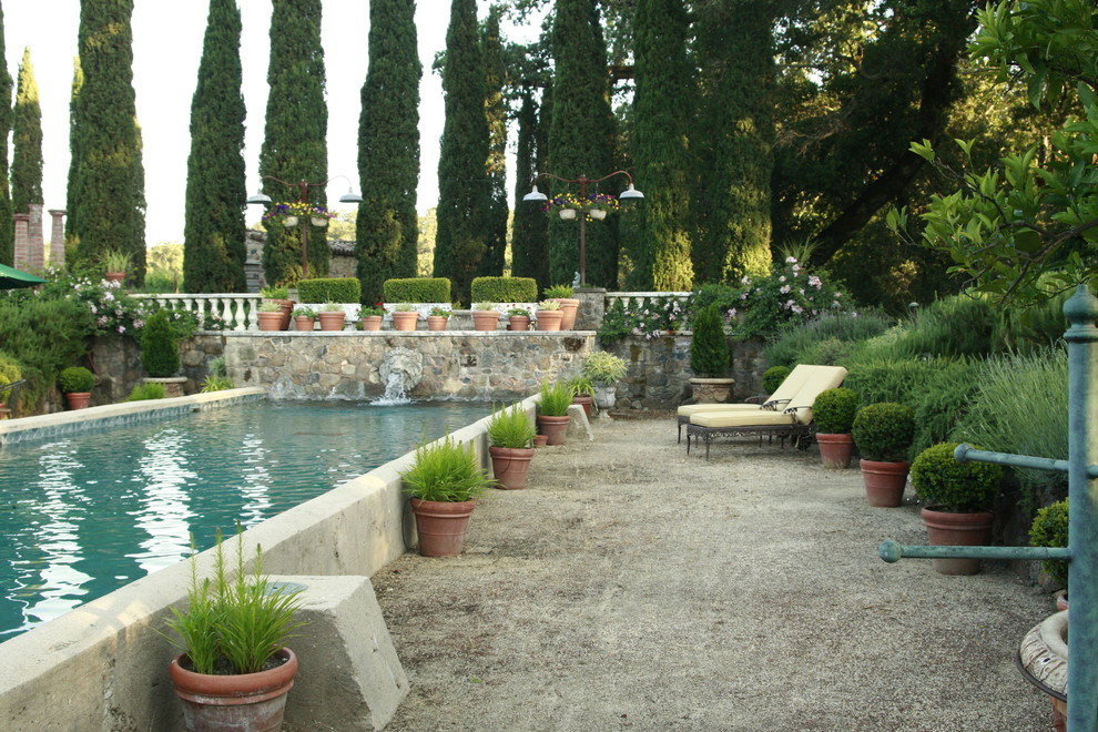 Exempel på en mellanstor medelhavsstil rektangulär träningspool på baksidan av huset, med en fontän och grus
