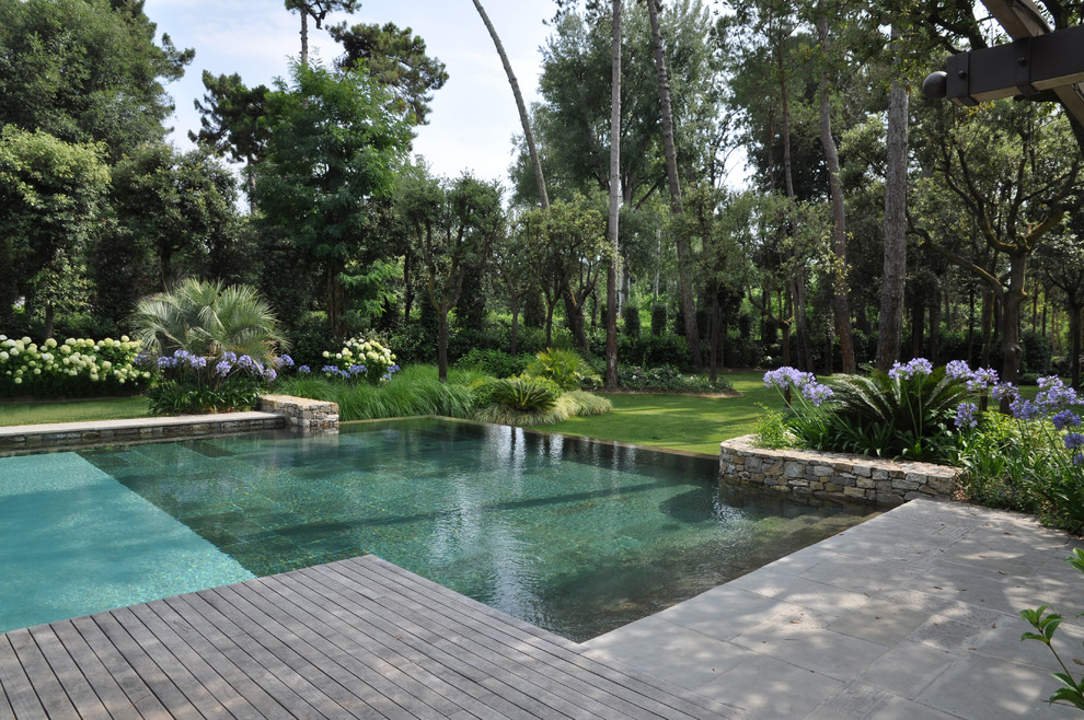 Idée de décoration pour une très grande piscine à débordement design rectangle avec une terrasse en bois.