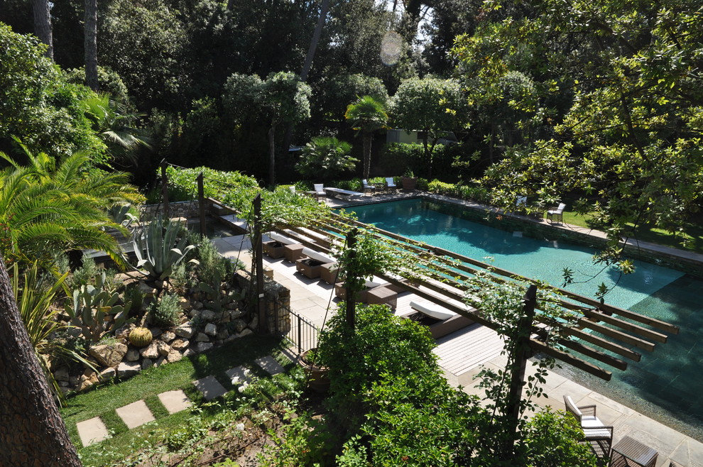 Modelo de casa de la piscina y piscina infinita actual extra grande rectangular en patio delantero con adoquines de piedra natural