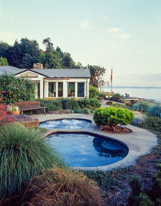 Cette photo montre une grande piscine naturelle et arrière chic ronde avec un bain bouillonnant et des pavés en pierre naturelle.