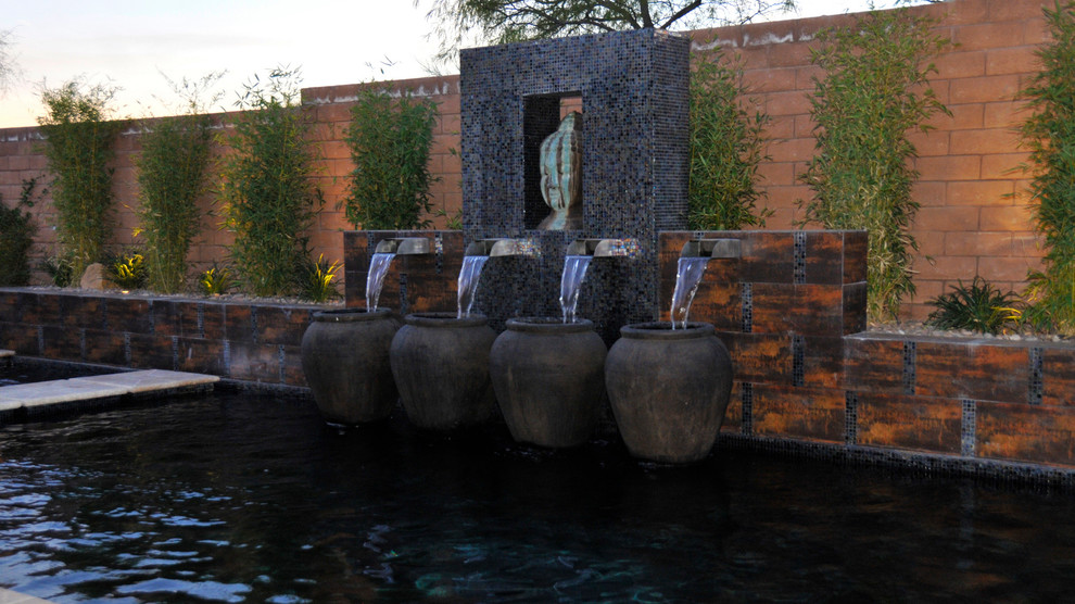 Cette photo montre une grande piscine arrière tendance rectangle avec un point d'eau et des pavés en pierre naturelle.