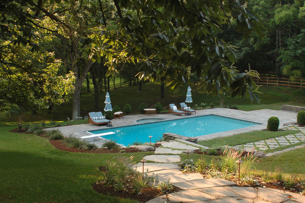 На фото: большой спортивный, прямоугольный бассейн на заднем дворе в классическом стиле с джакузи и покрытием из каменной брусчатки с