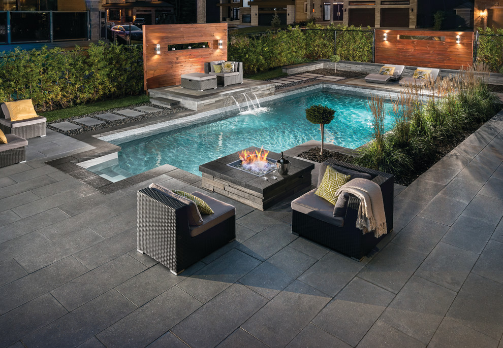 Imagen de piscina con fuente alargada minimalista de tamaño medio en forma de L en patio trasero con adoquines de hormigón