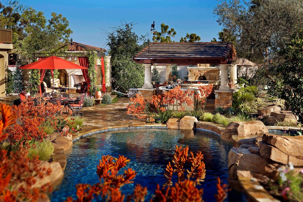 Diseño de piscina natural tradicional grande a medida en patio trasero con adoquines de piedra natural